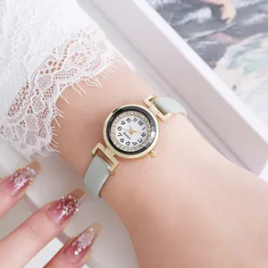 Close-up of a mint green leather strap watch with rhinestone bezel on a woman's wrist