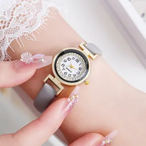 Detailed close-up of a ladies gold quartz watch with a diamond bezel and grey leather strap