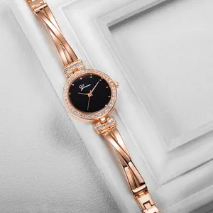 Detail of rose gold bangle watch with crystal-encrusted bezel and black dial