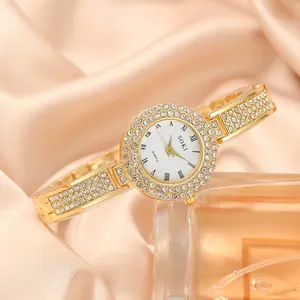 Dettaglio di un orologio al quarzo dorato da donna con castone in cristallo su seta rosa