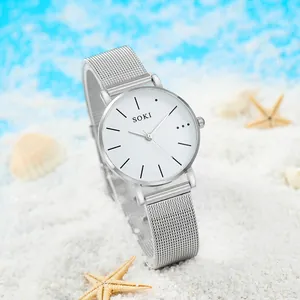 Montre SOKI argentée avec bracelet en maille sur sable blanc avec coquillages de mer