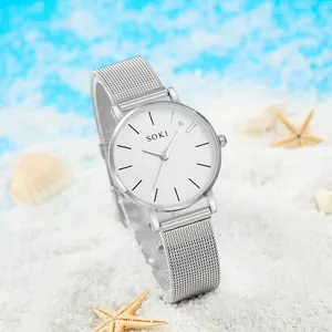 Montre élégante pour femme avec bracelet argenté à mailles et cadran blanc sur plage