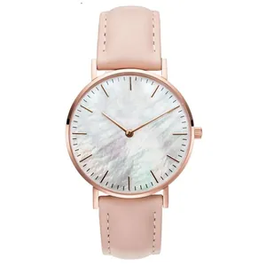 Close-up of minimalist rose gold watch with white pearlescent dial and pink leather strap