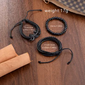 Three-piece men's black braided leather bracelet set with infinity charm on wood background