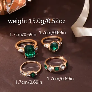 Macro detail of four gold plated rings set with green gemstones and zircon accents