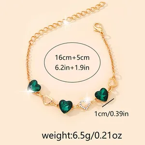 Detail of gold heart bracelet showing size dimensions and green gemstone charms