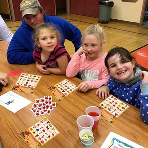 Family playing Thanksgiving Bingo game with colorful maple leaf cards and turkey motifs