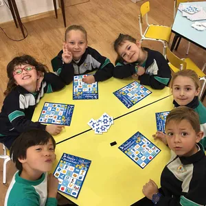 Bambini giocano a bingo di Hanukkah con carte blu e segnalini a stella su tavolo giallo