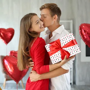 Romantic Valentine’s Day gift box with red heart pattern and satin ribbon in couple scene