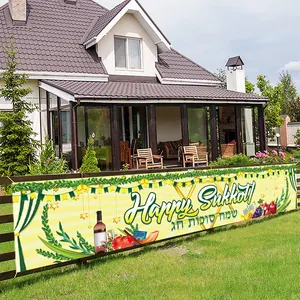 Outdoor Sukkot festival banner with ivy and fruit decorations on a garden fence