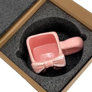 Vista dettagliata della tazza in ceramica con fiocco rosa confezionata in schiuma protettiva