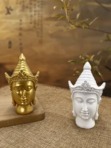 Close-up of golden and white Buddha head statues with intricate crown details on wood