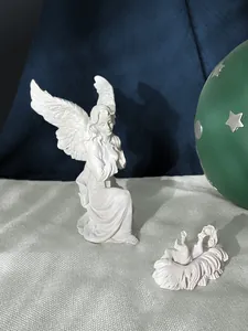 Macro detail of white resin angel statue with infant Jesus on festive blue velvet background