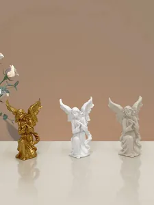 Dettaglio di tre statuette di angeli in resina oro e bianco con ali finemente lavorate
