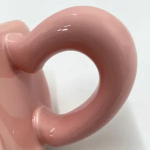 Dettaglio macro del manico della tazza in ceramica rosa lucida con finitura liscia
