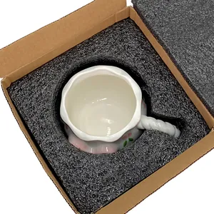 Keramiktasse mit floralem Relief und gewelltem Rand in sicherer Schaumstoffverpackung