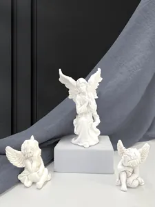 Detail of three white resin angel figurines in prayer and sleeping poses for home decor