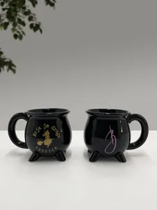 Detailansicht schwarzer Keramiktassen in Hexenkessel-Optik mit goldener Aufschrift