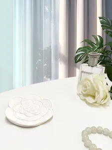 Dettaglio vassoio per gioielli in resina bianca a forma di camelia con texture di petali