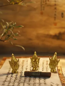 Detailed close-up of three golden resin Buddha head statues on a vintage calligraphy scroll