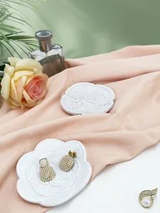 Dettaglio ravvicinato di orecchini di perle e spilla di strass su piatto decorativo in ceramica
