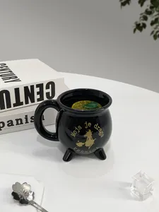 Detail einer schwarzen Keramiktasse in Hexenkessel-Form mit goldenem Hexenmotiv