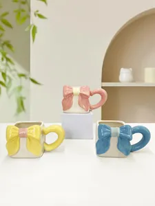 Dettaglio di tazze in ceramica con fiocchi 3D nei colori rosa giallo e blu