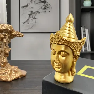 Golden Southeast Asian Buddha head statue ornament on a sleek black decorative base