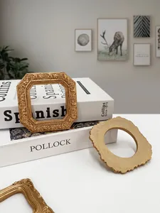 Close-up of vintage gold resin frames with ornate carvings on white books