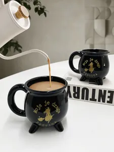 Detailansicht der schwarzen Hexenkessel-Tasse aus Keramik mit Golddruck und drei Füßen