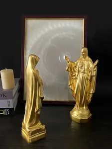 Dettaglio di statuette dorate di Gesù e Maria su un tavolo di legno e libri d'epoca