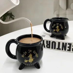 Keramikbecher in Hexenkessel-Form mit goldenem Schriftzug und Hexen-Silhouette in Schwarz