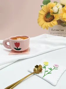 Dettaglio tazza in ceramica a tulipano rosa con bordo ondulato e cucchiaio d'oro