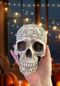 Close-up of Celtic knot carvings on a resin skull figurine held by hand for Halloween decor