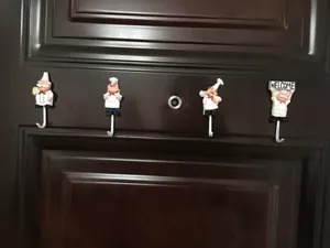 Set di quattro ganci da parete in resina a forma di chef montati su porta in legno scuro