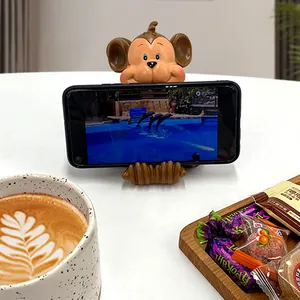 Creative resin monkey phone stand in a cozy desktop setting with coffee and snacks