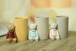 Detailed view of three cute cartoon bear resin pencil holders on a wooden desk setup