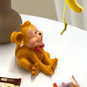 Close-up of a cute yellow monkey resin phone holder with a red bow tie on a desk