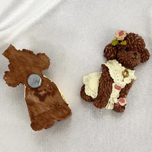 Front and back detail of a resin poodle fridge magnet with brown fur and lace dress