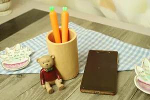 Detail of wooden bear pencil holder set with carrot pens on a blue checkered mat