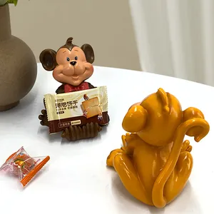 Close-up of two creative monkey resin stands used for holding snacks and cards on a desk