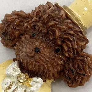Close-up of a brown resin poodle fridge magnet with a yellow hat and bow tie