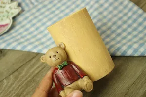 Detail of creative resin pen holder with a cute 3D cartoon bear on wood-grain texture