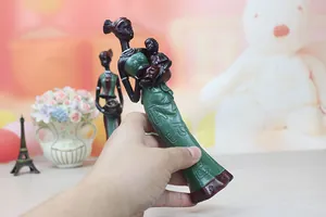 Detail of African resin mother and child figurine in green dress held by hand