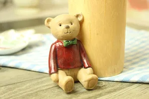 Close-up of cute bear figurine with red sweater and green bowtie, resin wood-like texture