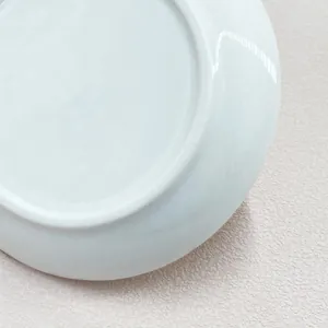 Macro view of polished white ceramic jewelry dish base with smooth glazed texture