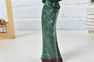 Macro shot of dark green resin figurine with 3D embossed letters and matte texture finish