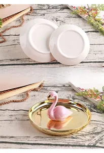 Detailed view of pink flamingo relief on a golden ceramic jewelry dish for rings
