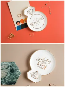 Detail of white ceramic jewelry tray with gold rim and engagement-themed slogans