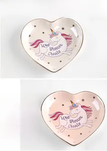 Macro view of heart-shaped ceramic jewelry dish with unicorn design and gold rim detail